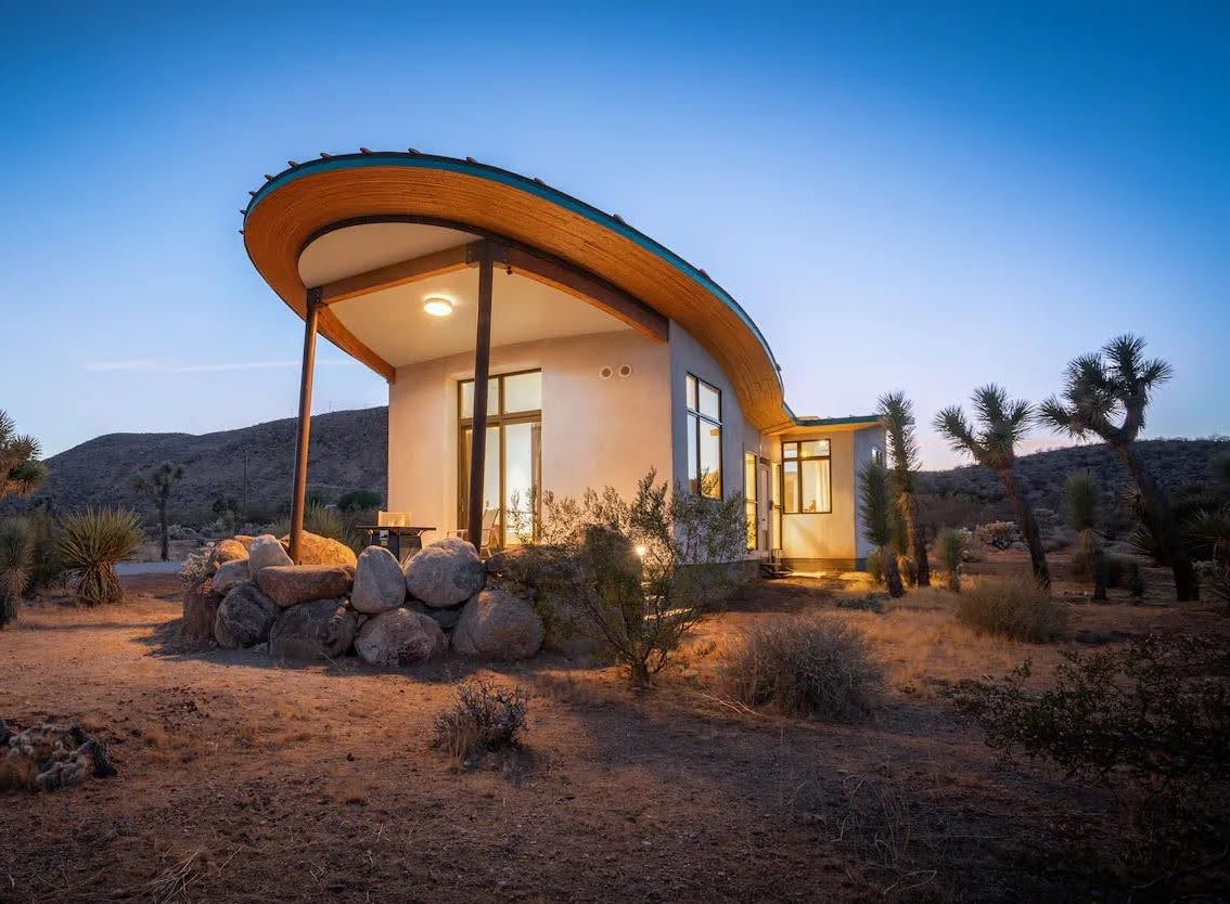 A radical strawbale cabin in the desert, has a butterfly roof and is covered in a natural lime plaster.