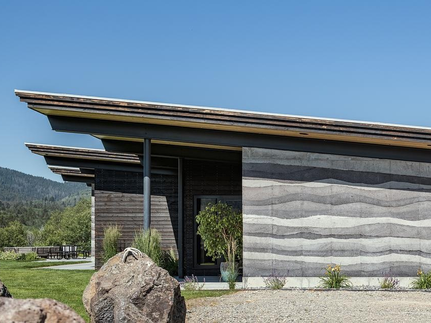 Rammed earth walls, clean lines, cantilevered roofs, and durable Shou Sugi Ban siding define the exterior of this modern mountain house built for extreme conditions.