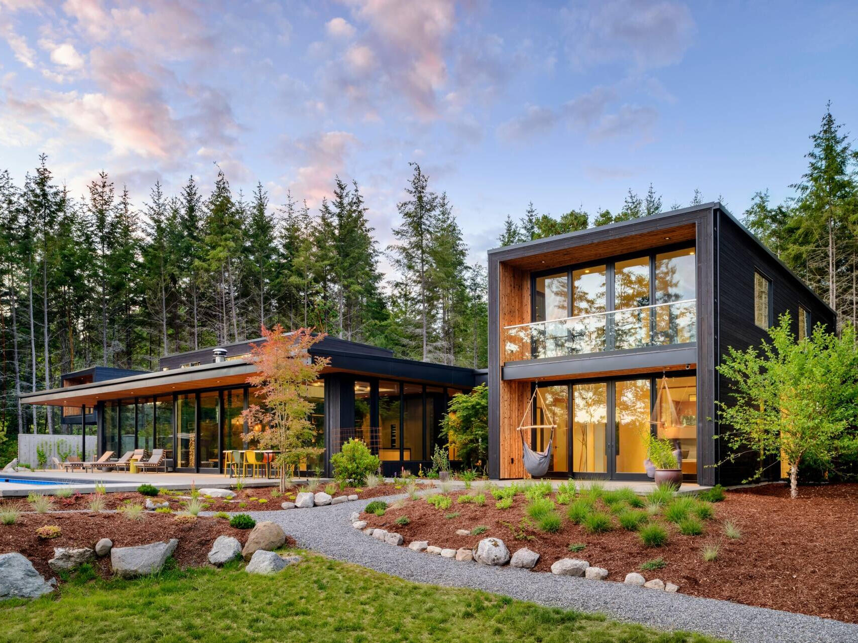 A stepped, low-profile home clad in charred yakisugi siding, designed to blend into the hillside and forest.