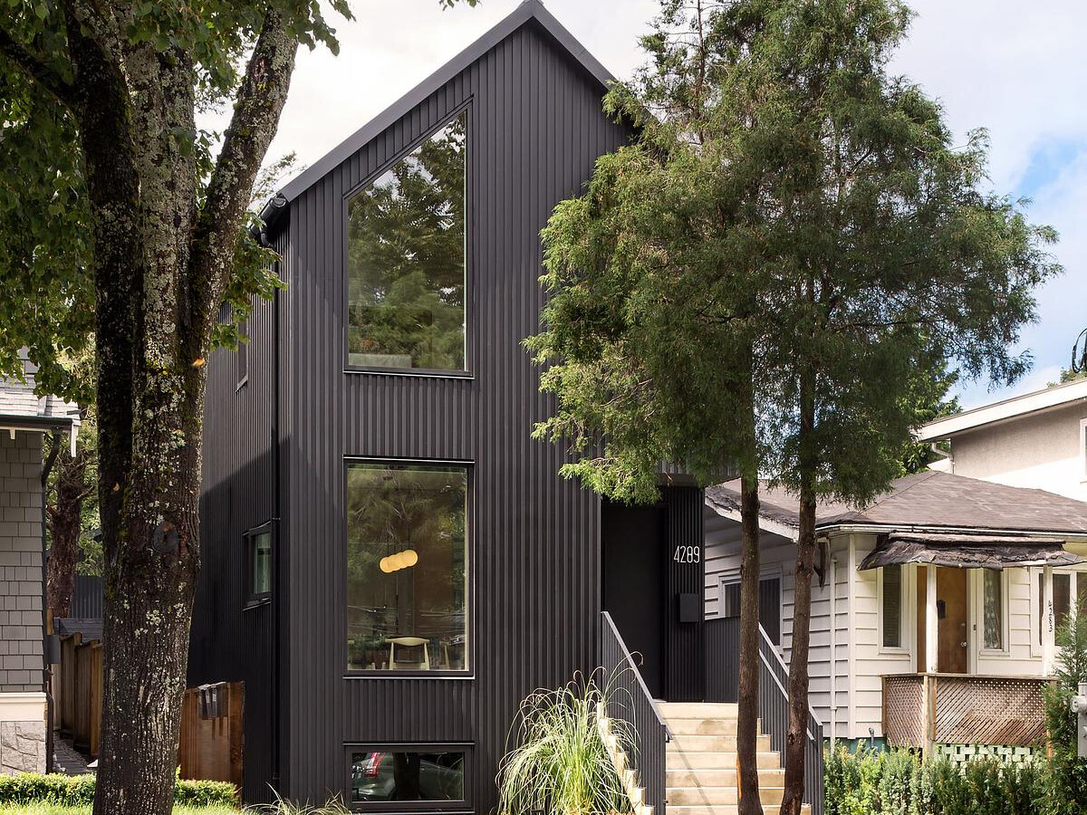 Black board and batten siding pairs with a matching metal roof for a crisp, modern exterior of this house, that feels timeless and tailored to the site.