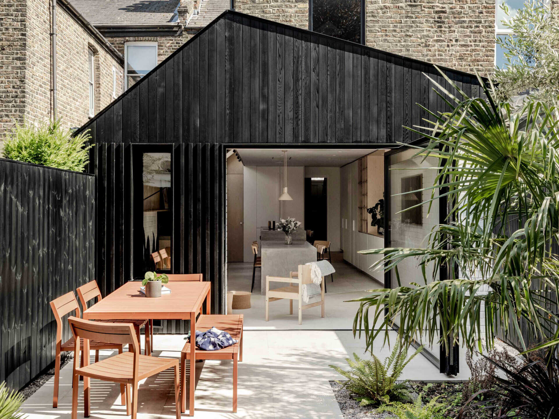 Clad in blackened cedar and filled with light, the new extension opens to the garden and unites kitchen, dining, and living into one calm space.