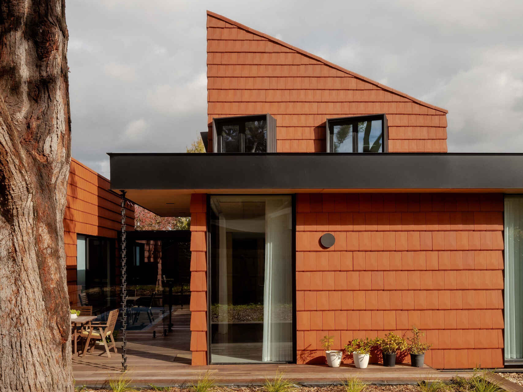 Discover how this Melbourne home uses terracotta shingles on both roof and walls, blending sustainable materials with a warm, natural palette rooted in the surrounding trees.