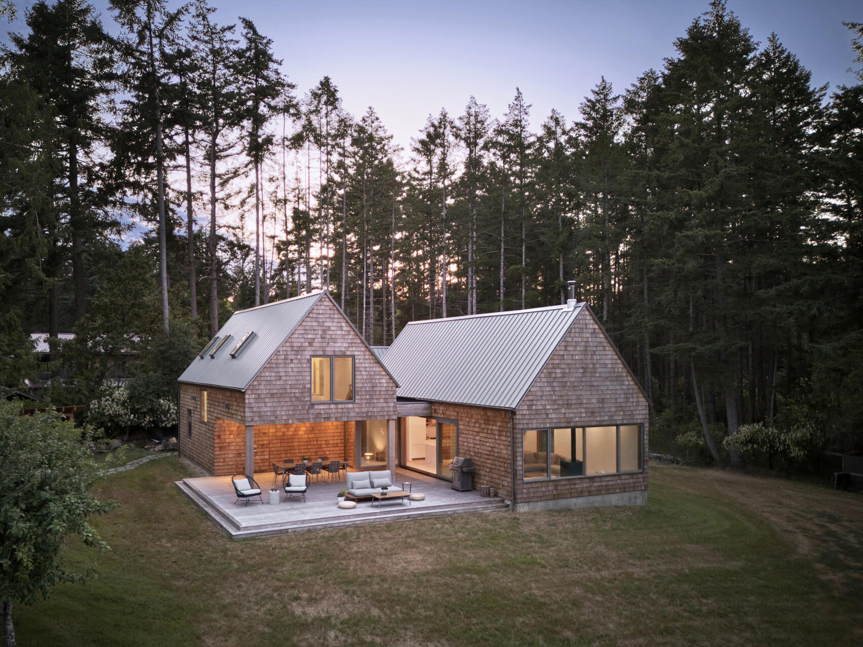 The exterior of this modern cabin  is clad in natural cedar shingles, giving the modern form a timeless texture that resonates with the forest surroundings. 