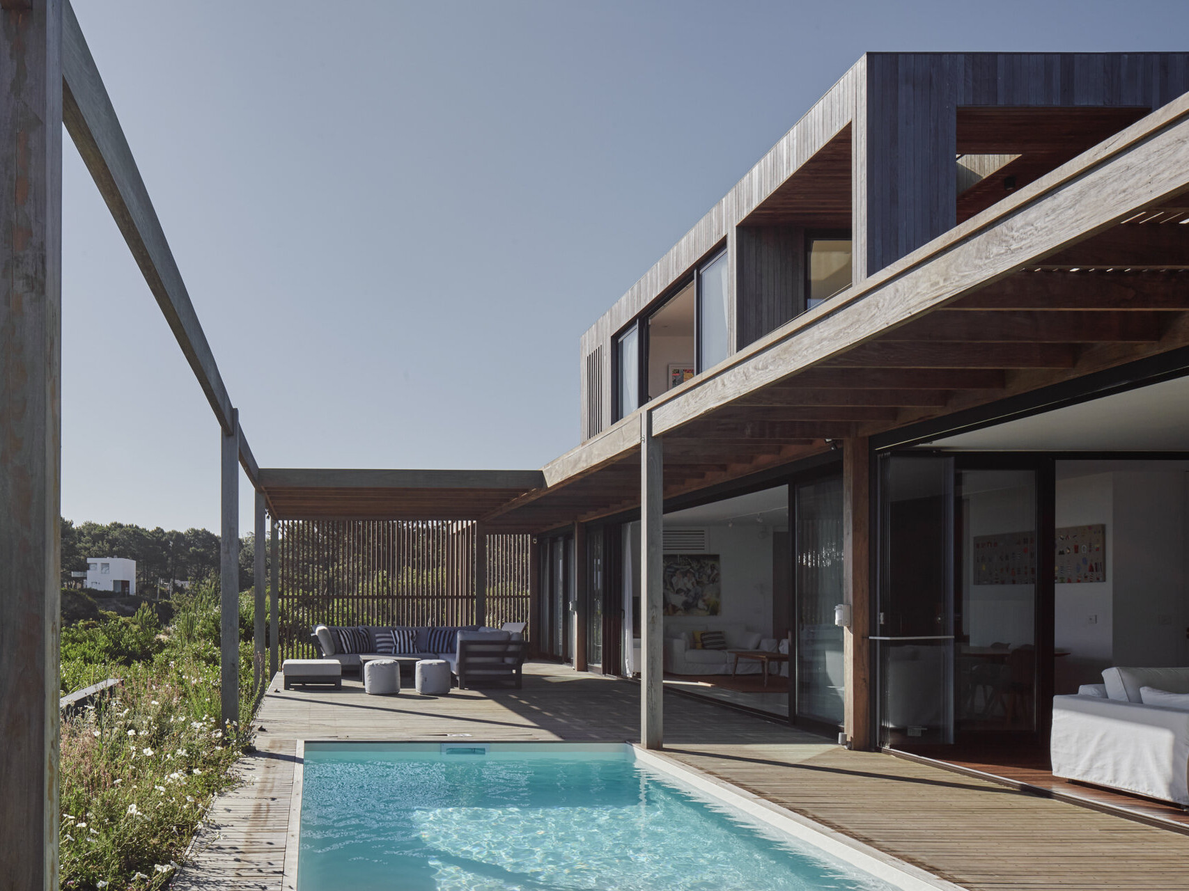 This prefabricated modular house, clad in wood, preserves the sandy terrain while opening all rooms toward the sea.