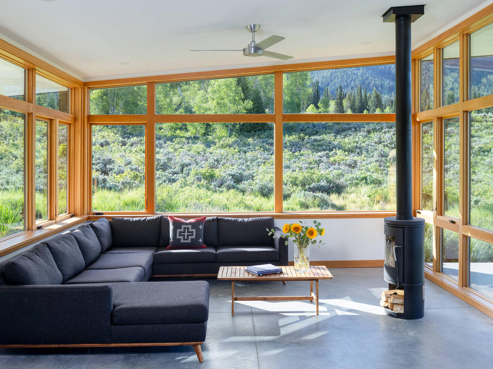 This living room in an off-grid cabin features southwest-facing windows that frame sweeping canyon views and fill the space with natural light.