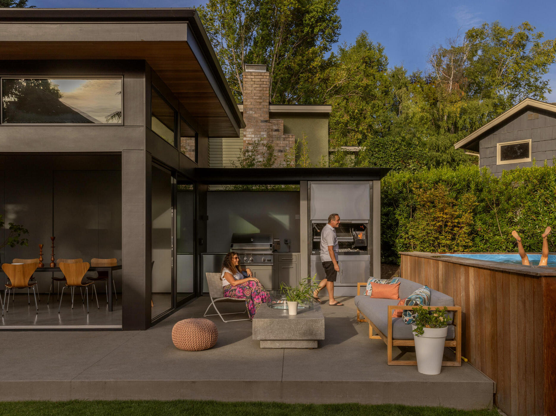 Seamless indoor-outdoor living with sliding glass doors, lawn, fire table, and swim spa, perfect for family gatherings and entertaining.