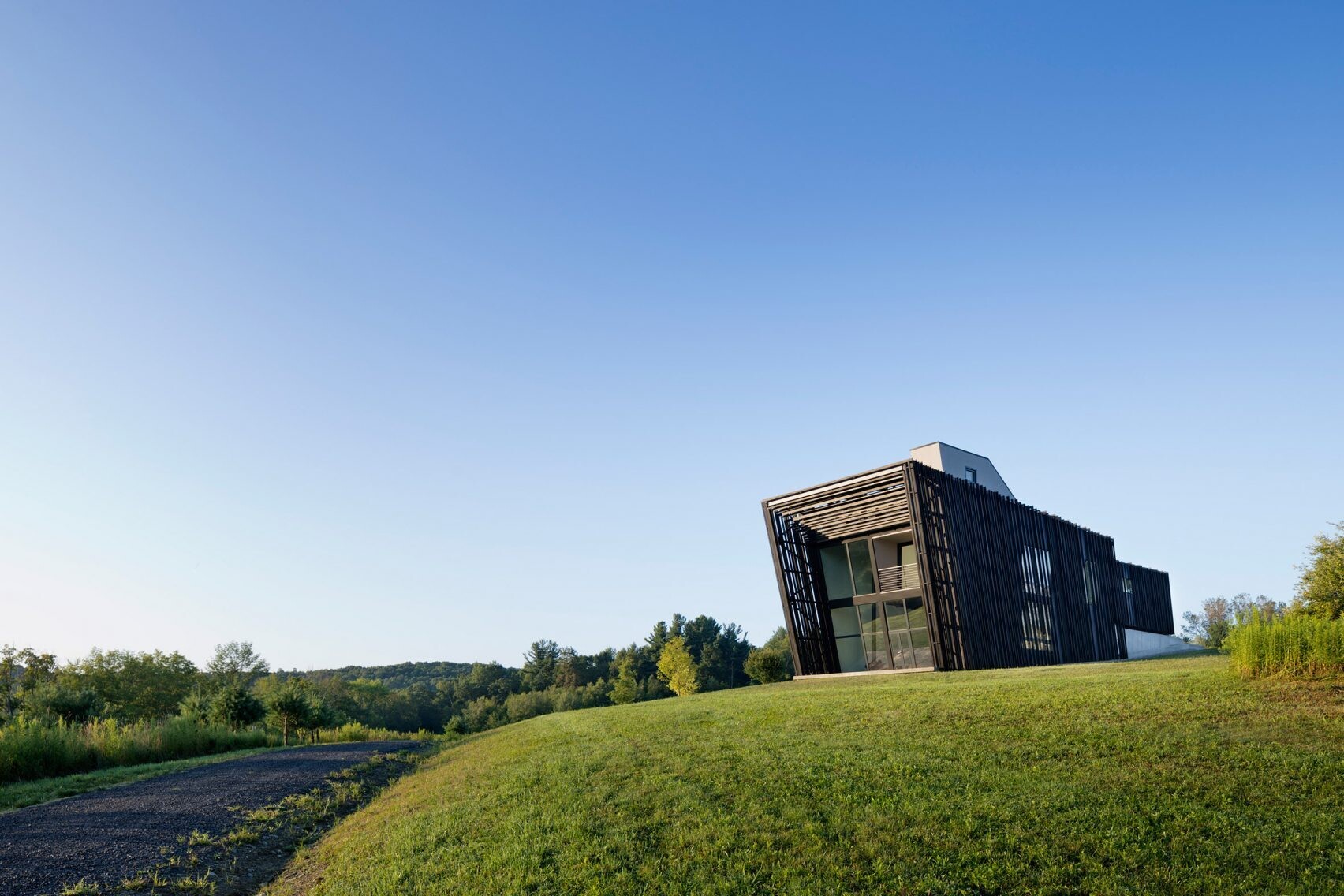 Wrapped in charred timber and set on a concrete base, this sculptural hillside home stands as a minimalist landmark in New York’s Hudson Valley.