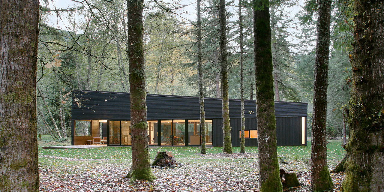 A sleek, single-story house by Robert Hutchison Architecture, wrapped in blackened cedar and nestled quietly among the evergreens near Mount Rainier.