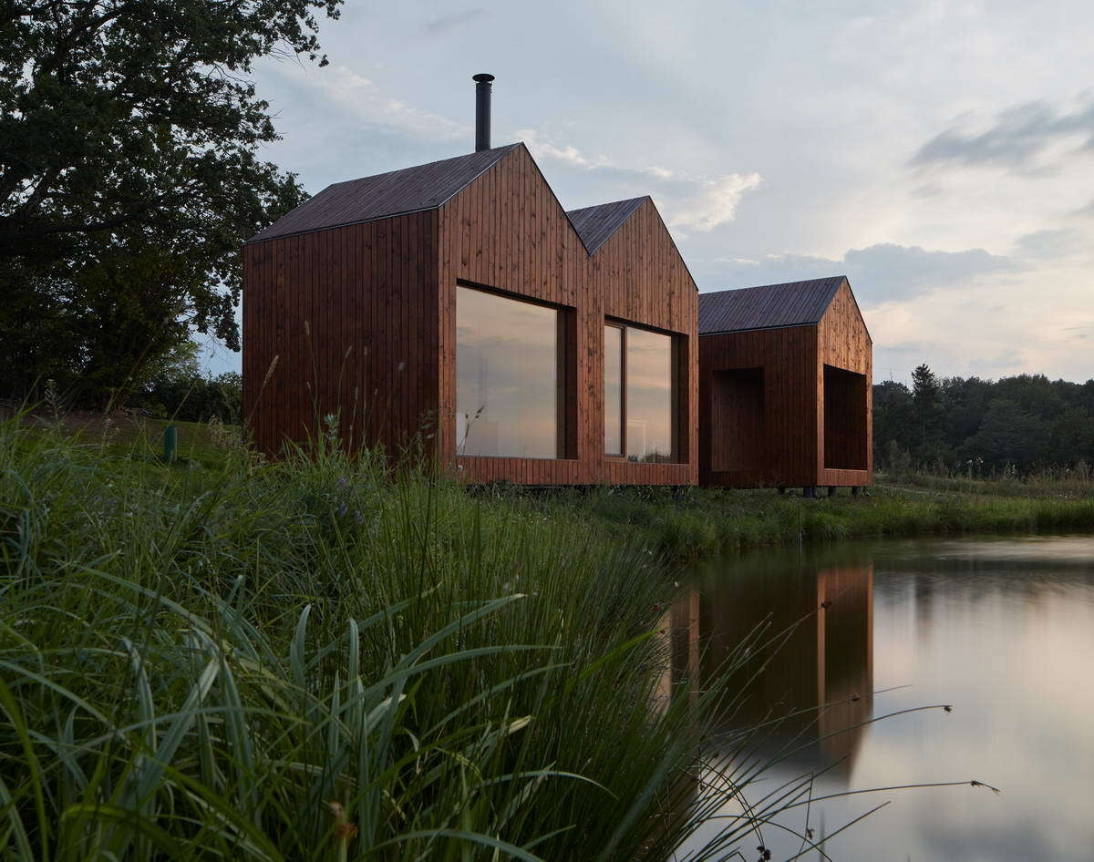 A clever cottage layout inspired by traditional fisherman’s cabins, connecting interiors with pond views and sunlit oak surroundings.