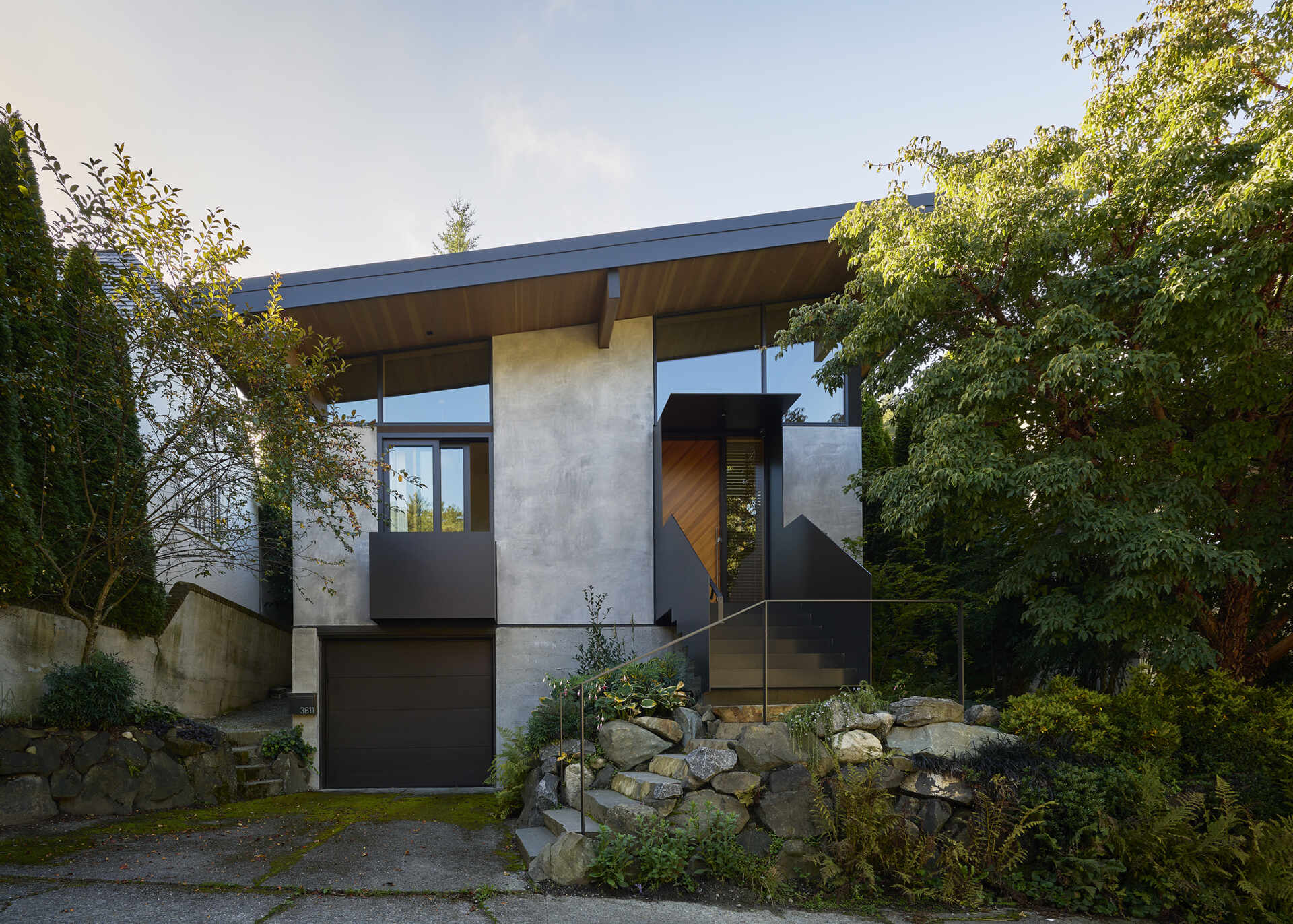 Elevated entry with stairs leads to a light-filled Seattle home with high shed roof and clerestory windows