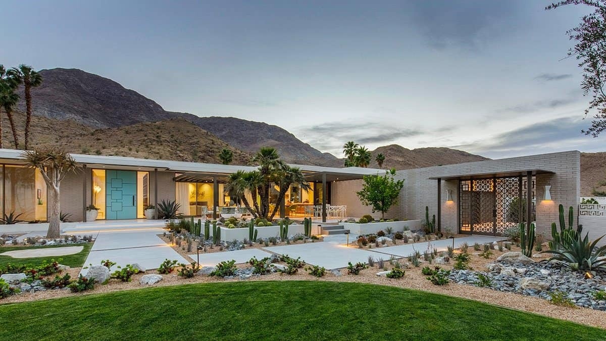 A mid century modern exterior in Rancho Mirage featuring brick, stucco, painted steel, and concrete walkways set against the desert landscape.