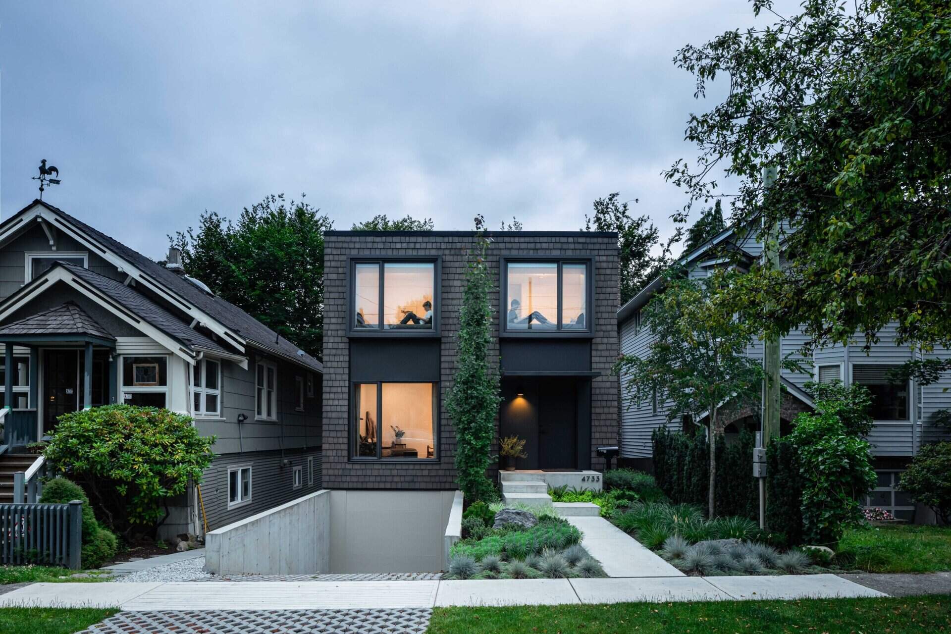 A dark shingled infill home in Vancouver designed to sit quietly between a 1900s house and a 1980s neighbor, balancing symmetry and modern form.