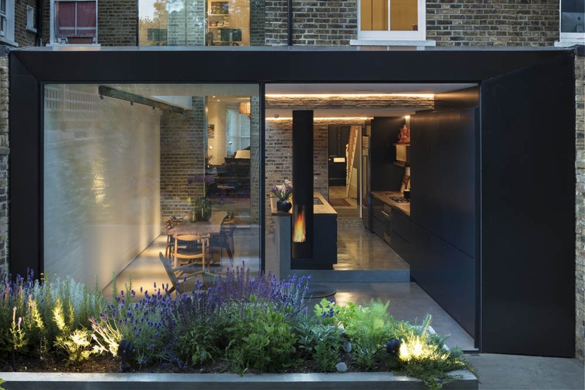 A dramatic double height frameless glass extension transforms a traditional London Victorian home into a light filled contemporary space.