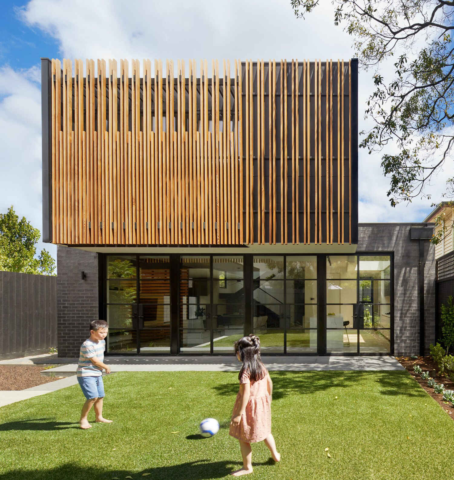 Vertical timber battens wrap the upper level of this Melbourne extension, adding warmth, texture and privacy to the master bedroom while softening the modern form.
