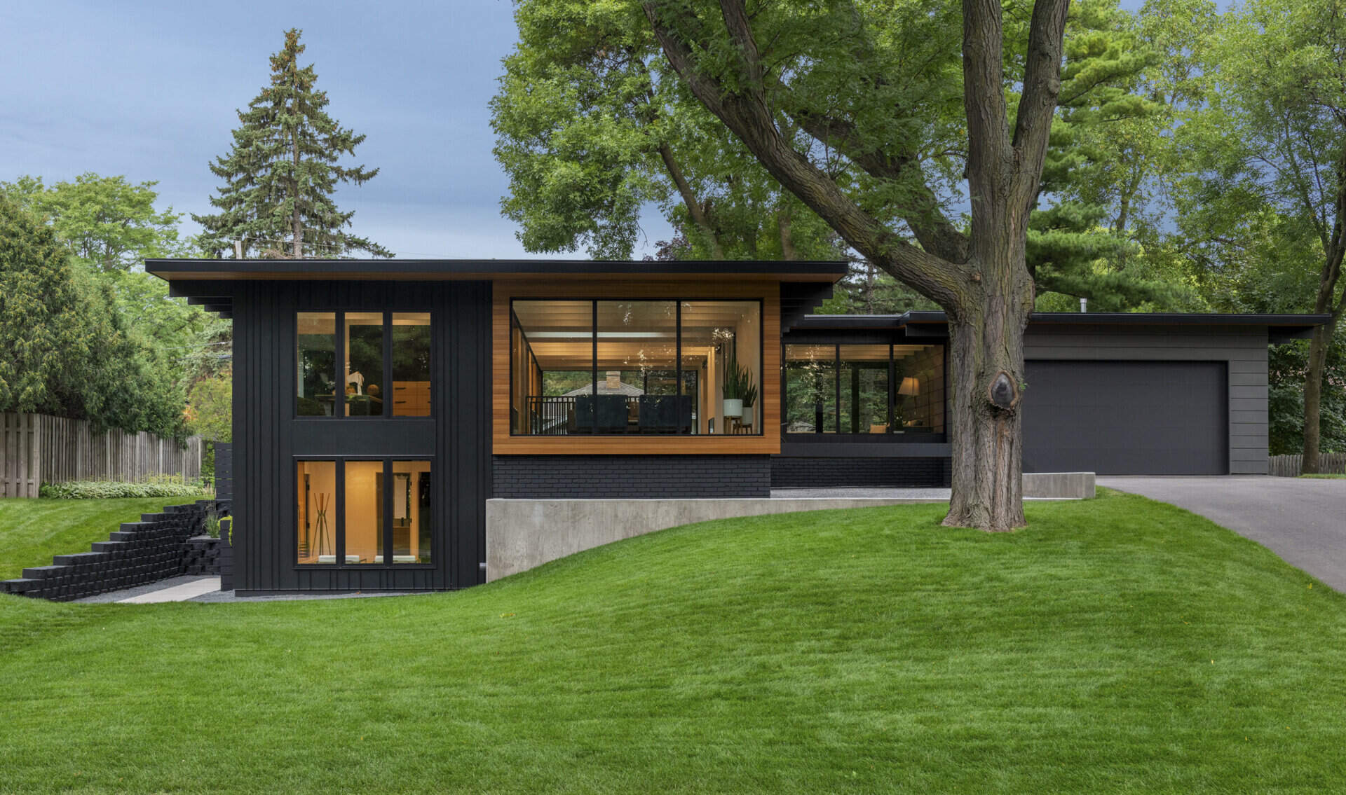 The black and wood exterior of this Golden Valley home stands out against mature trees and a spacious yard.