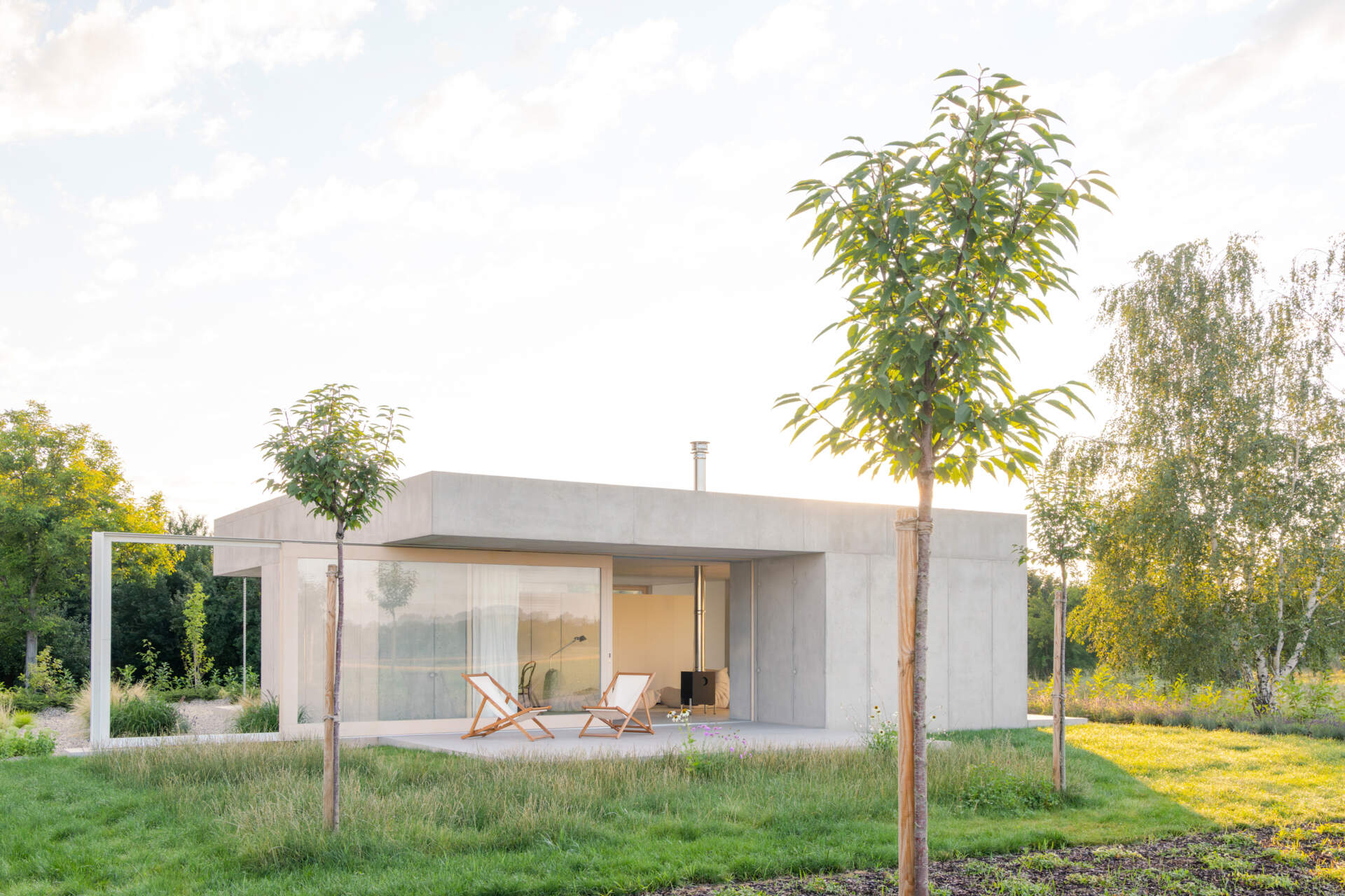 Low and horizontal, this small one bedroom concrete house uses three structural cores and a sliding glass wall to open the entire living space directly to the garden.