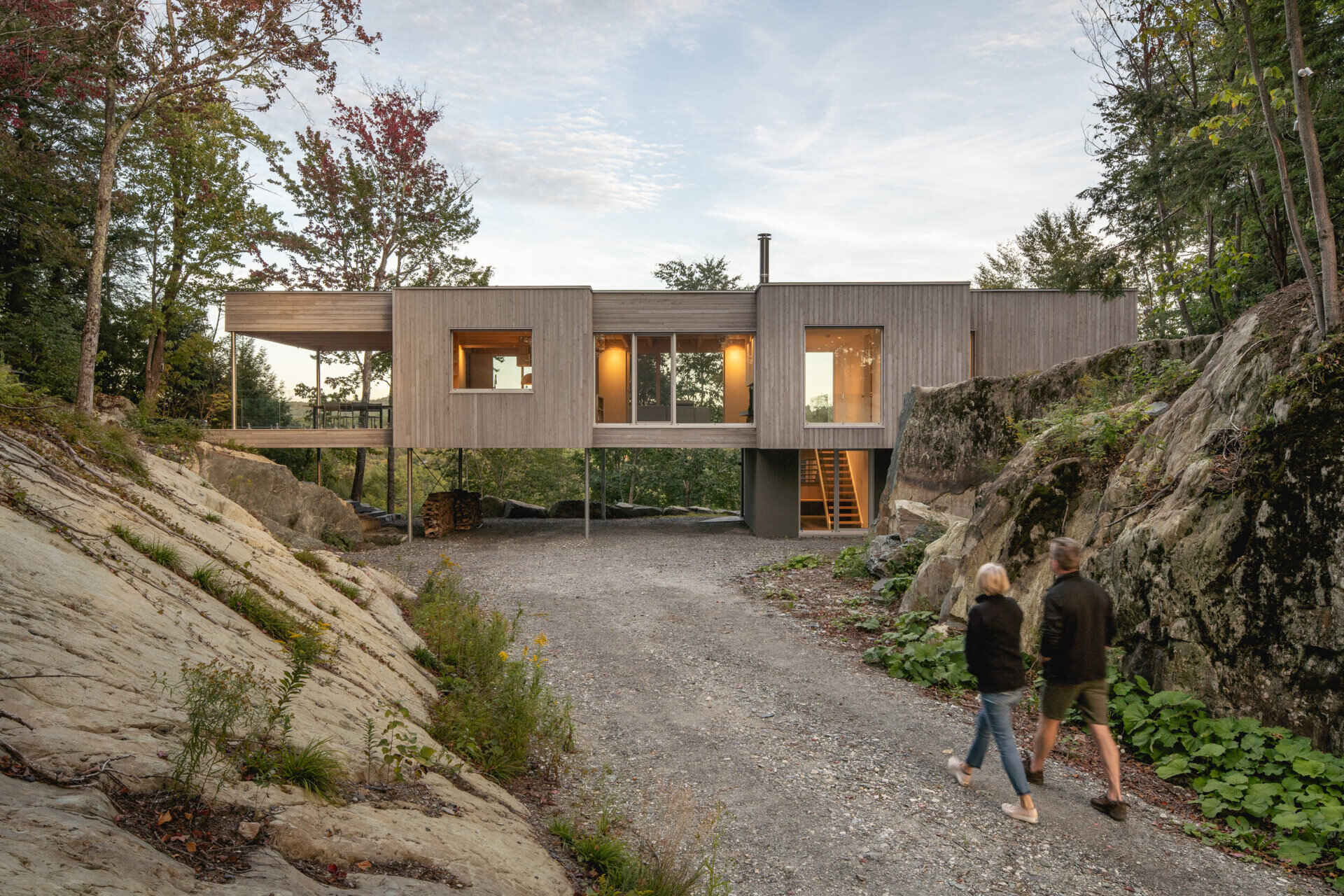 Weathered cedar cladding helps this forest home blend into the surrounding landscape while its elevated structure follows the natural rock formations.