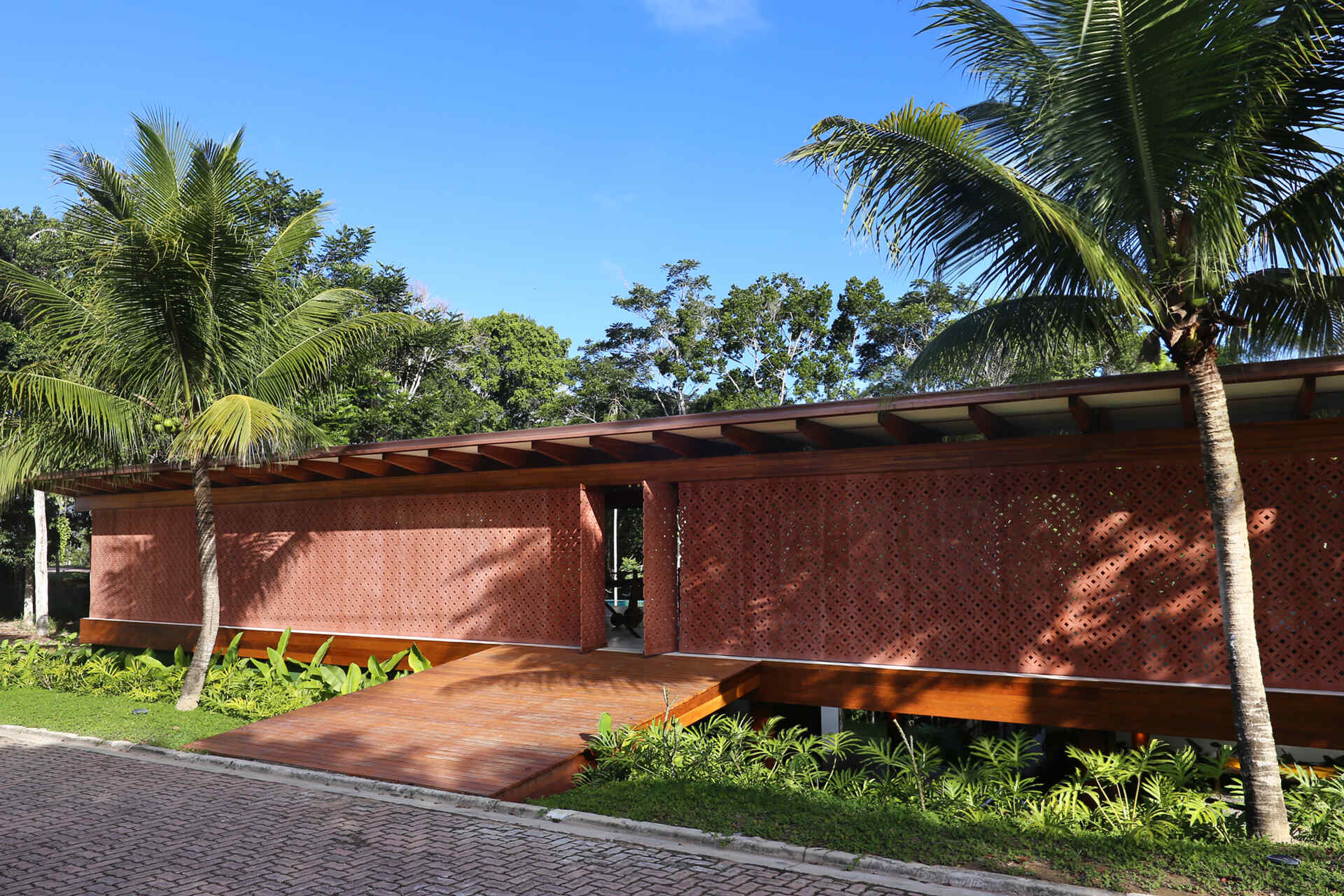 Take a tour of Muxarabi House in Trancoso, Brazil, where eucalyptus timber, handcrafted interiors, geometric façade screens and a rooftop garden come together in one contemporary beach home.